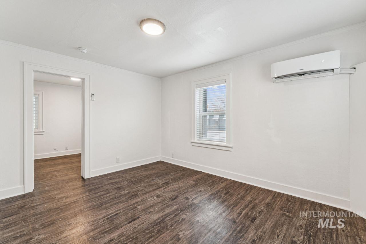 911 2nd Street South Nampa, ID 83651 - Photo 35 of 50 Spare room with dark wood-style flooring, an AC wall unit, and crown molding