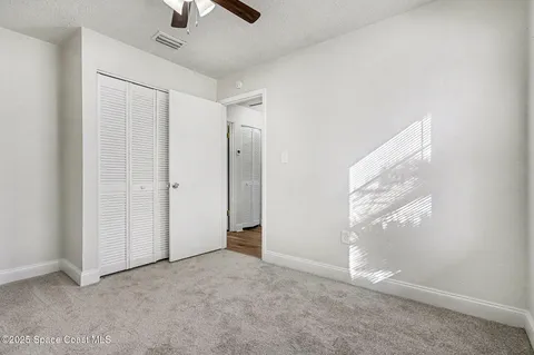 an empty room with windows and fan