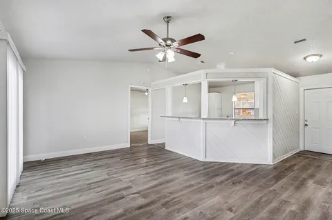 a view of empty room with wooden floor and ceiling fan