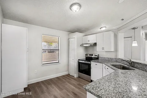 a kitchen with granite countertop a sink stove and refrigerator
