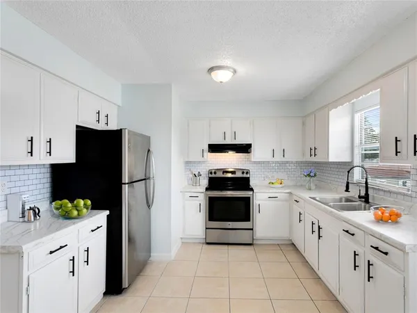 a kitchen with stainless steel appliances a refrigerator sink and white cabinets