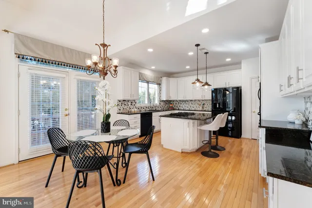 a kitchen with a dining table chairs wooden floor and appliances