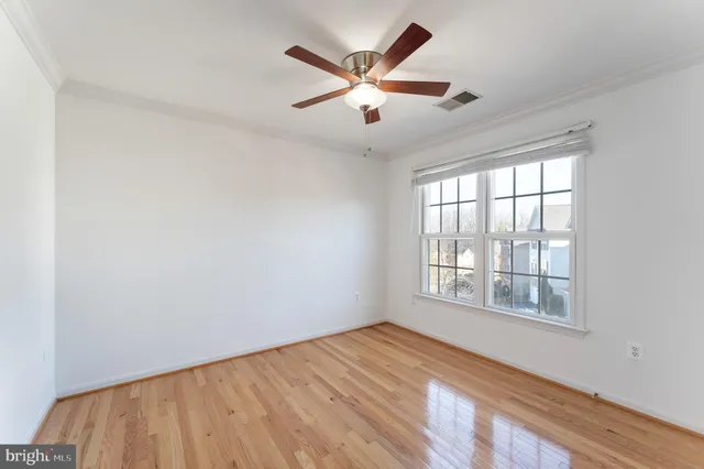 an empty room with wooden floor fan and windows
