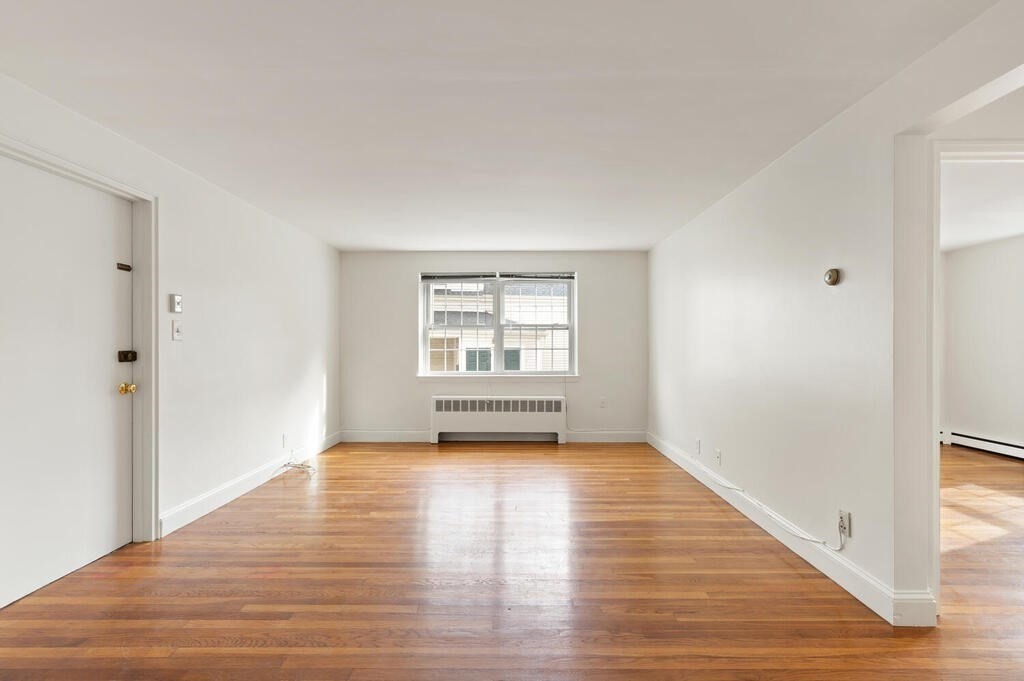 4 Menotomy Road, Unit 5 Arlington, MA 02476 - Photo 4 of 13 a view of an empty room with wooden floor and a window