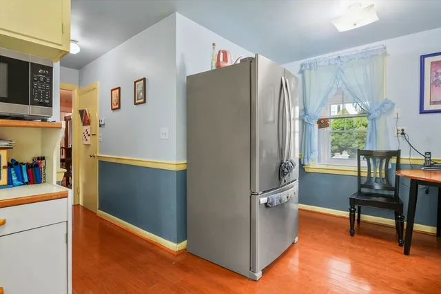 a kitchen with stainless steel appliances granite countertop a refrigerator a stove a sink dishwasher and white cabinets with wooden floor