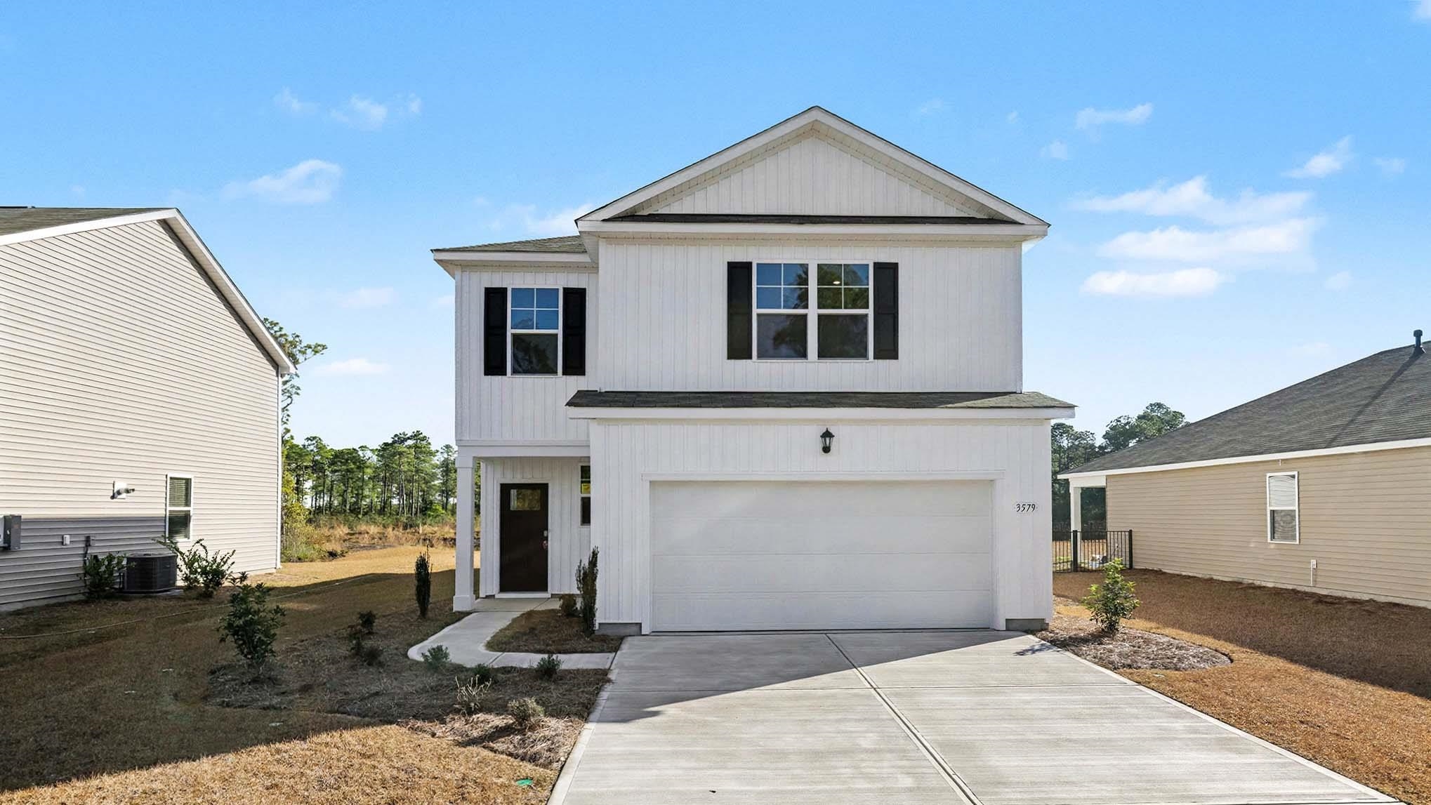 View of front of home with concrete driveway and a garage