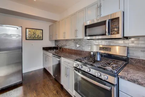 a kitchen with stainless steel appliances granite countertop a stove microwave and sink