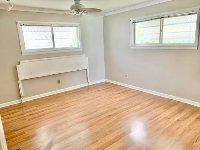 an empty room with wooden floor cabinet and windows