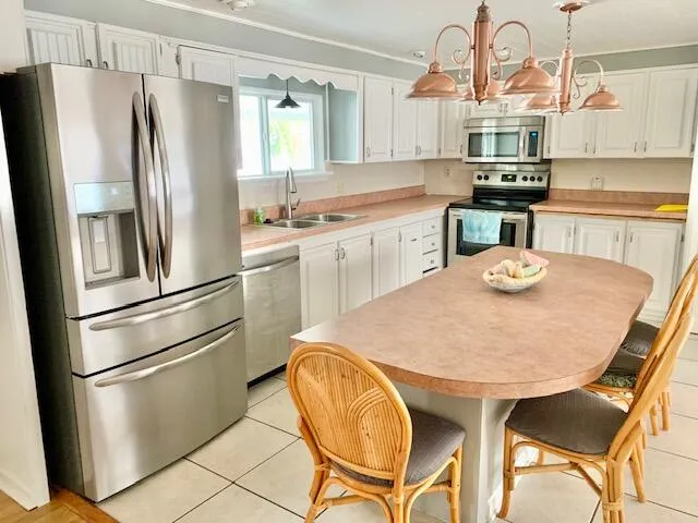 a kitchen with stainless steel appliances granite countertop a dining table chairs refrigerator and cabinets