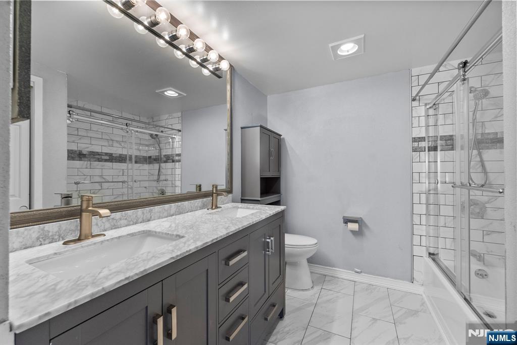 753 Summer, Unit 3D Newark, NJ 07104 - Photo 28 of 41 a bathroom with a granite countertop sink a mirror a toilet and shower
