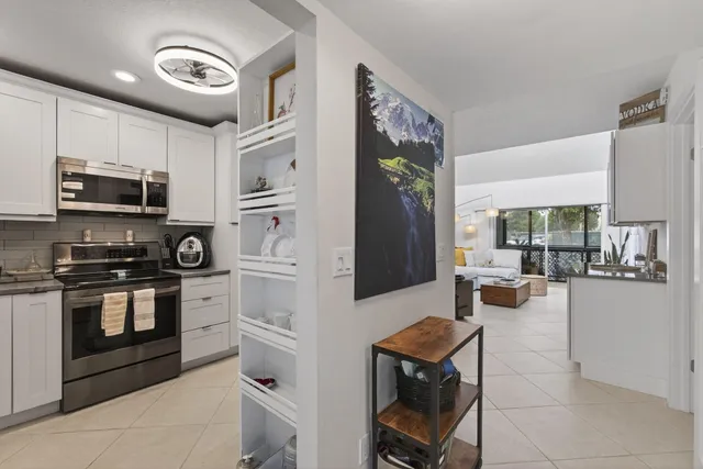 a kitchen with stainless steel appliances granite countertop a stove top oven a sink a stove a dining table and chairs