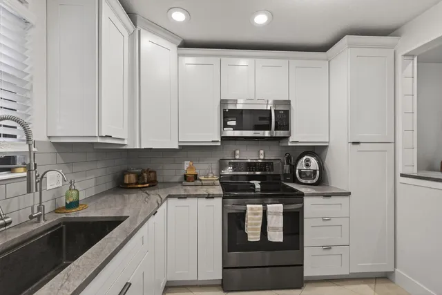 a kitchen with granite countertop white cabinets stainless steel appliances and sink