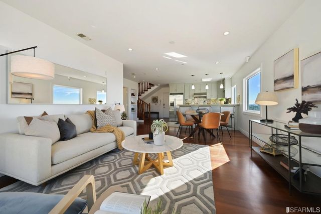 a living room with furniture kitchen view and a wooden floor