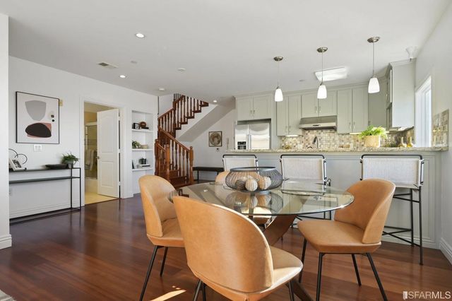 a kitchen with stainless steel appliances granite countertop a dining table chairs refrigerator and sink