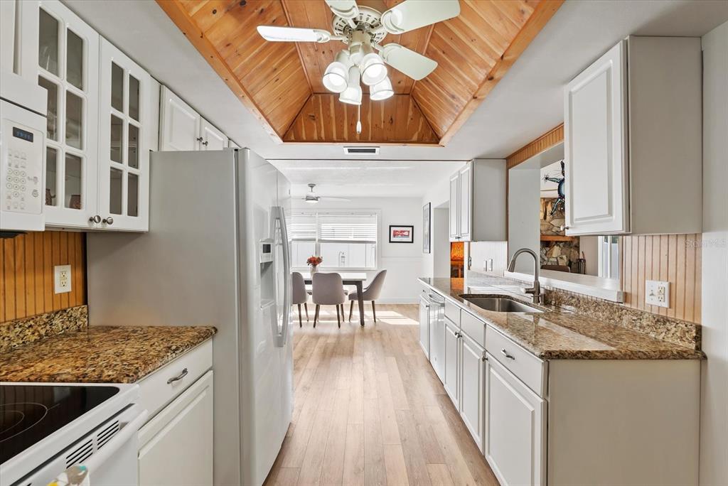 1700 Patricia Avenue Dunedin, FL 34698 - Photo 9 of 31 a kitchen with stainless steel appliances granite countertop a stove a sink dishwasher and a refrigerator with wooden floor