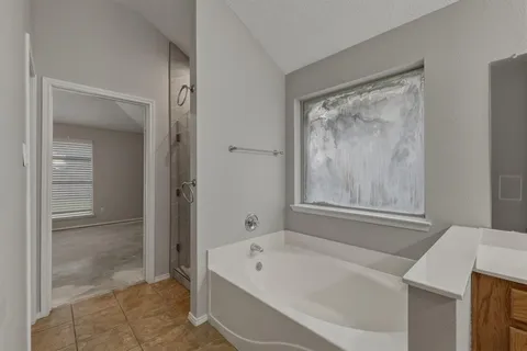 a bathroom with a tub a sink and glass door