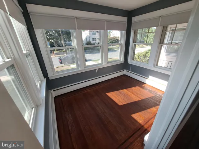 a view of an empty room with wooden floor and windows