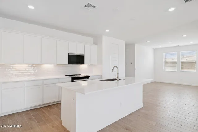 a kitchen with stainless steel appliances a stove top oven a sink a counter space and cabinets