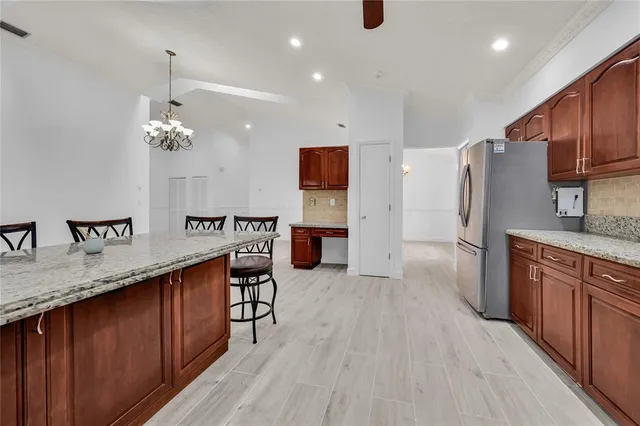 a kitchen with stainless steel appliances granite countertop a refrigerator a sink dishwasher and wooden cabinets with wooden floor