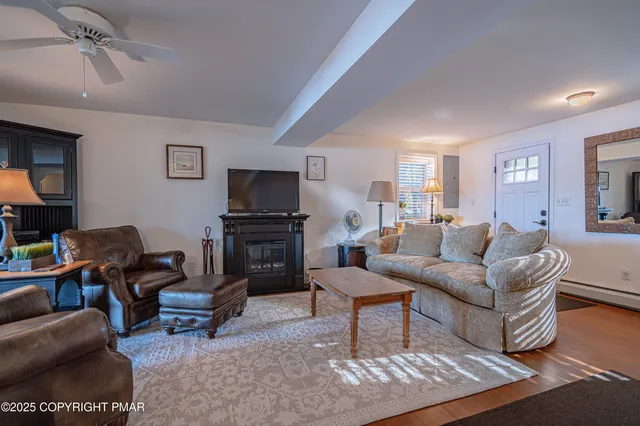a living room with furniture a rug a fireplace and a large window