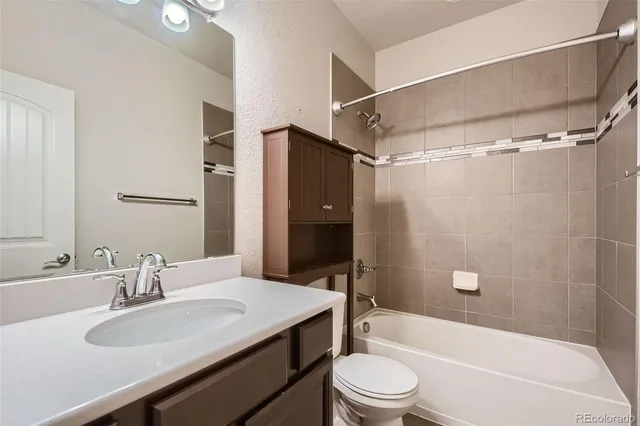 a bathroom with a granite countertop bathtub shower sink vanity and toilet