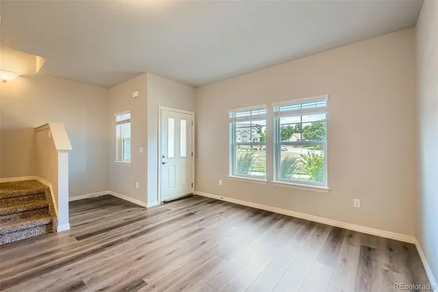 an empty room with wooden floor and windows
