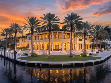a front view of a building with lake view and palm trees