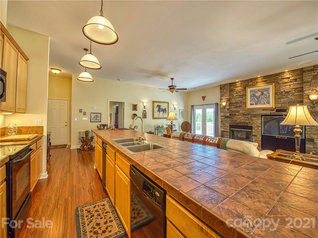 21 Rules Run Road Clyde, NC 28721 - Photo 12 of 32 a large kitchen with kitchen island a stove a sink a dining table and chairs with wooden floor
