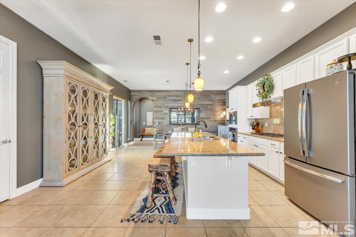 10675 Solano Court Reno, NV 89521 - Photo 13 of 39 a large kitchen with stainless steel appliances kitchen island granite countertop a refrigerator and a stove