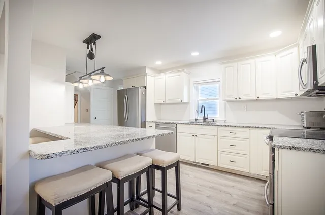a kitchen with kitchen island granite countertop a sink and white cabinets