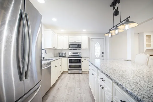 a kitchen with white cabinets and stainless steel appliances