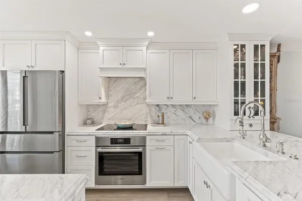 a kitchen with granite countertop a sink stainless steel appliances and white cabinets