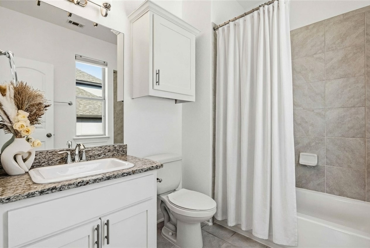 1517 Bardella Drive Leander, TX 78641 - Photo 22 of 40 Bathroom with vanity, shower / bath combination with curtain, and light tile patterned floors