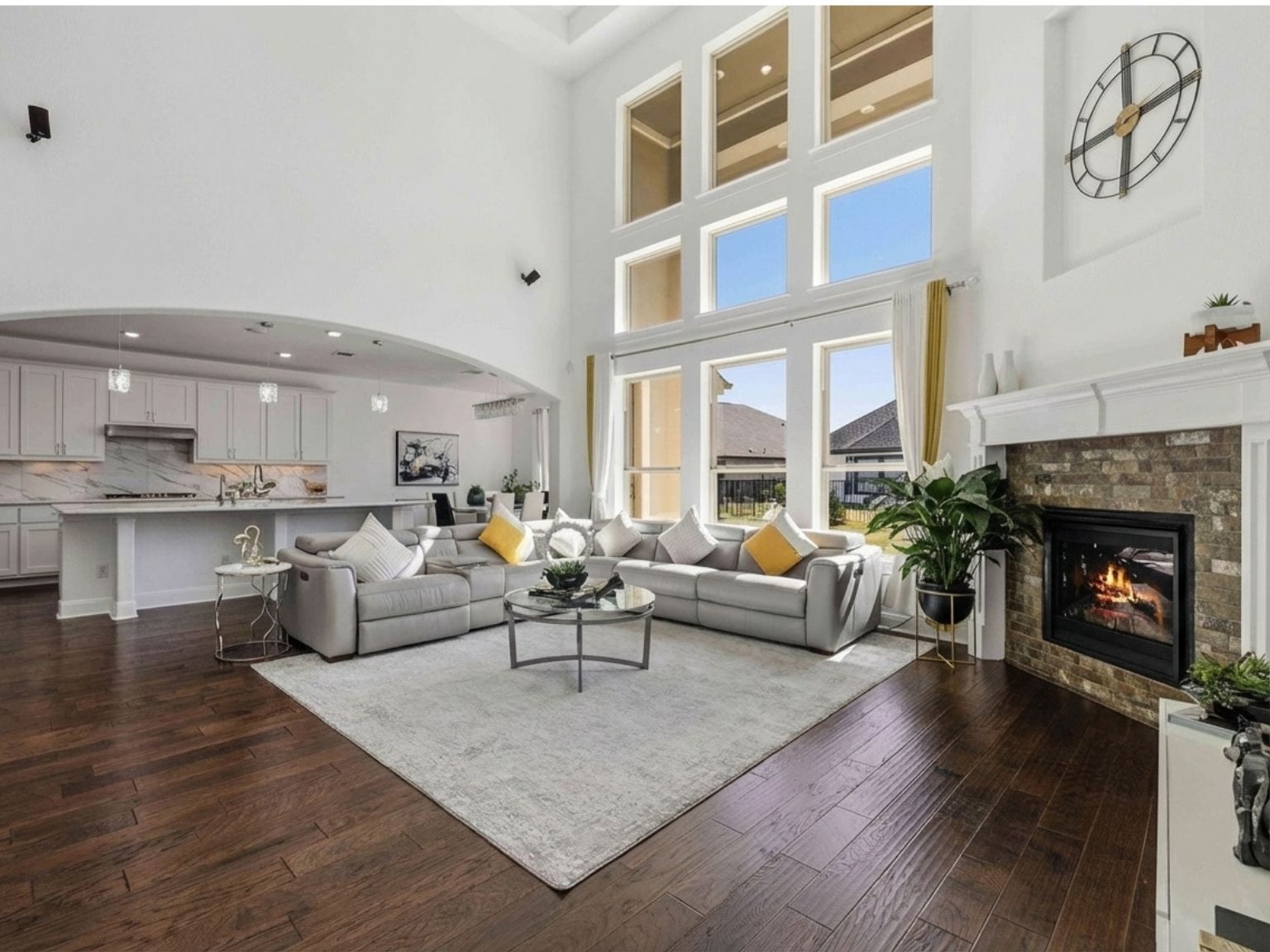1517 Bardella Drive Leander, TX 78641 - Photo 6 of 40 Living area featuring arched walkways, dark wood-type flooring, a glass covered fireplace, tray ceiling, and a high ceiling