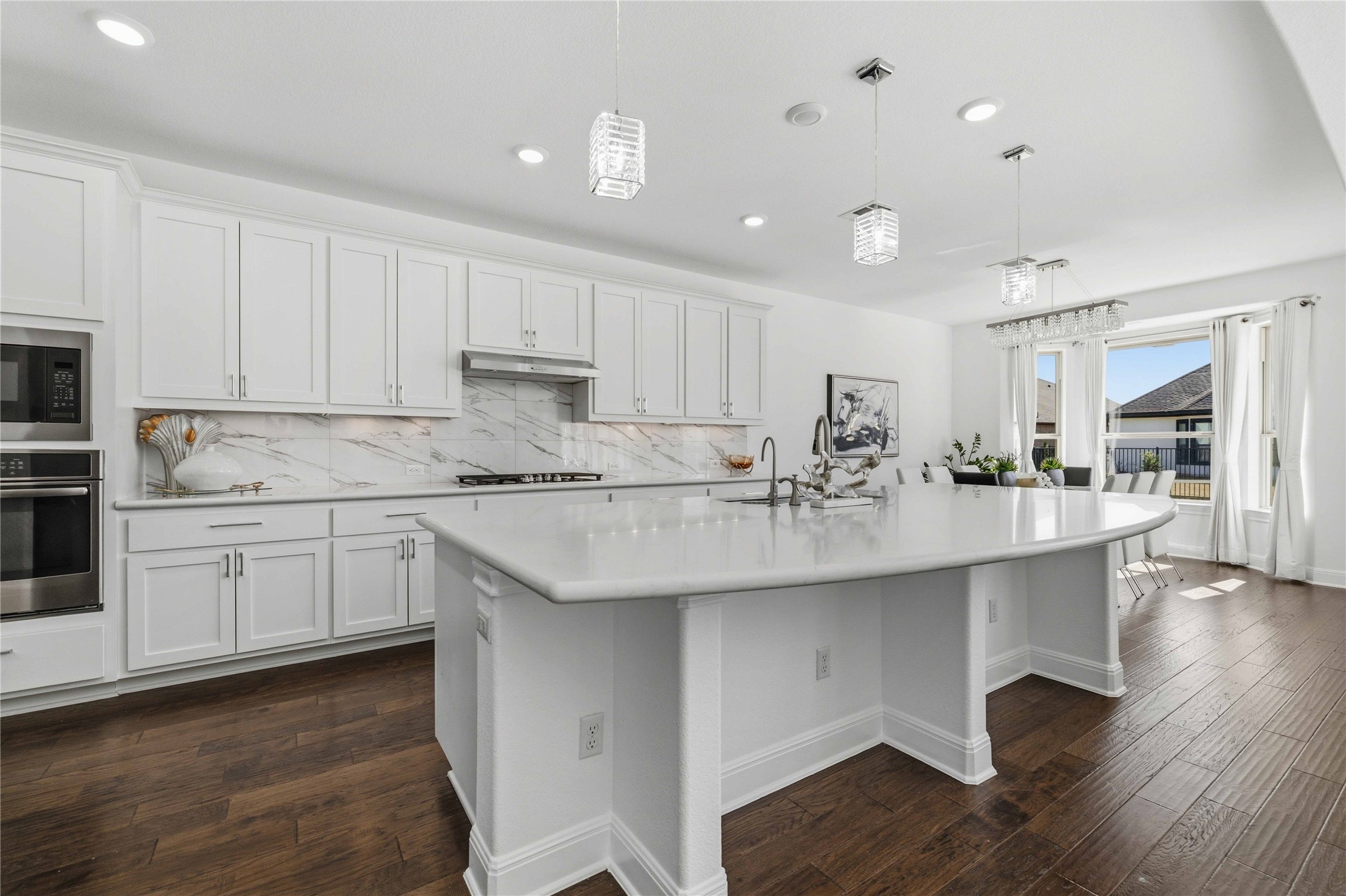 1517 Bardella Drive Leander, TX 78641 - Photo 8 of 40 Kitchen featuring white cabinetry, stainless steel appliances, oversized center island, porcelain tile backsplash and dark wood-style floors