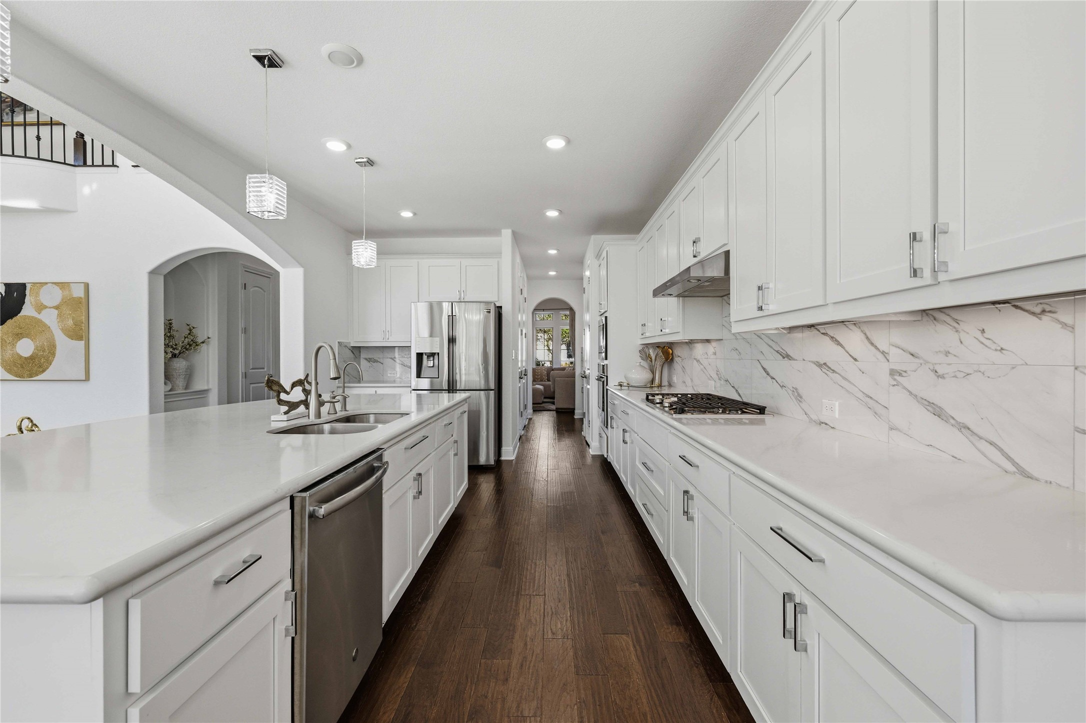 1517 Bardella Drive Leander, TX 78641 - Photo 9 of 40 Kitchen featuring arched walkways, a large island with sink, white cabinetry, stainless steel appliances, and dark wood-style floors