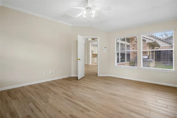 an empty room with wooden floor cabinet and windows
