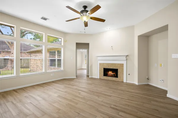 a view of a livingroom with a fireplace a ceiling fan and wooden floor