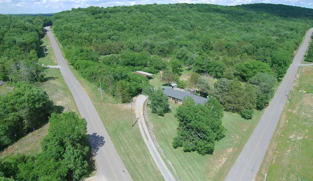 an aerial view of residential houses with outdoor space and trees