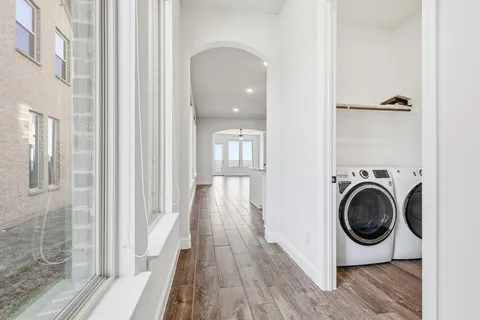 a view of a hallway with wooden floor and a bathroom