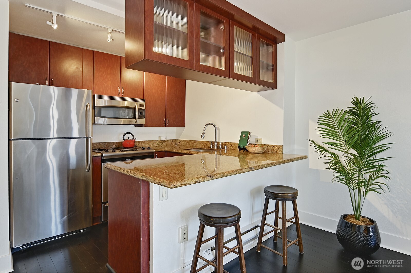 1105 Spring Street, Unit 709 Seattle, WA 98104 - Photo 8 of 30 a kitchen with stainless steel appliances a table and a refrigerator