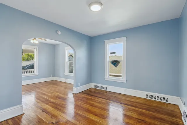 an empty room with wooden floor closet and windows