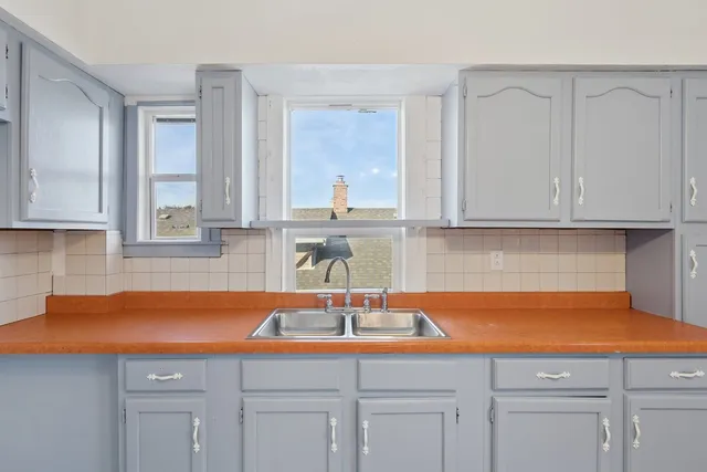 an empty room with wooden floor chandelier fan and windows