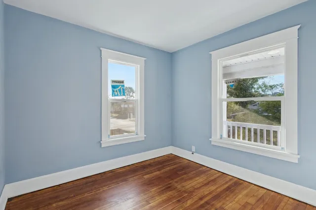 a view of an empty room with wooden floor and closet