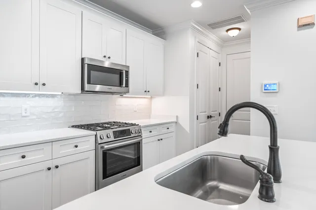 a kitchen with white cabinets a sink and white appliances