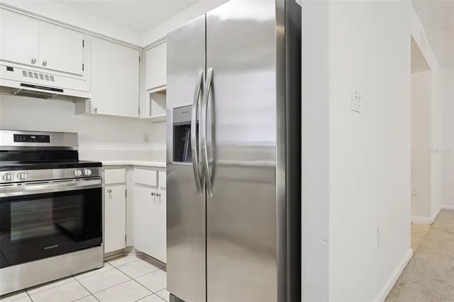 a kitchen with stainless steel appliances granite countertop a stove a refrigerator and a white cabinets
