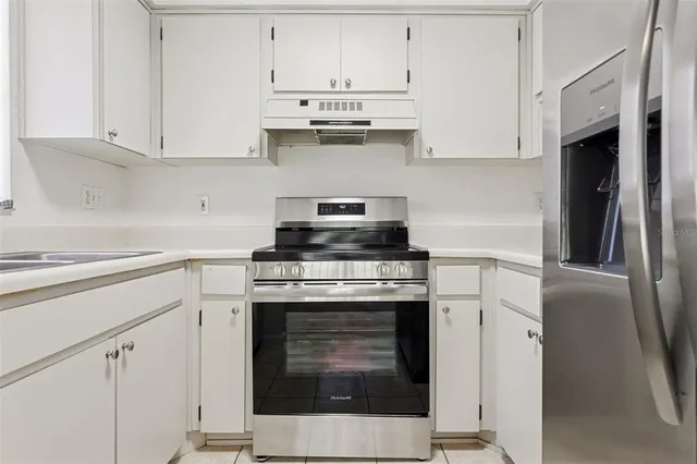 a view of an empty room with kitchen and window