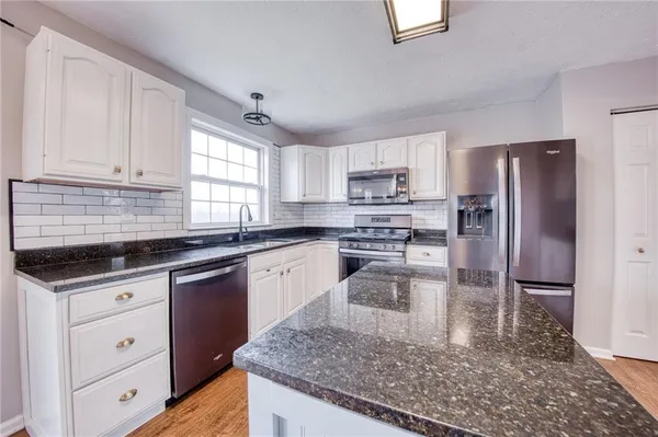 a kitchen with granite countertop a sink appliances cabinets and counter space