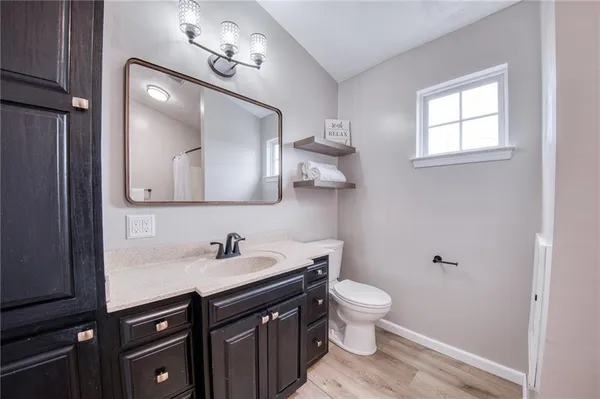 a bathroom with a toilet a sink a mirror and a window