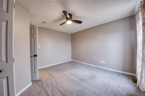 an empty room with ceiling fan and window